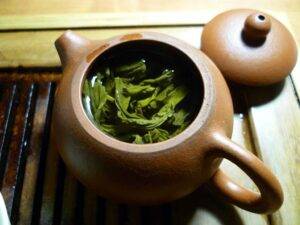 ใบไม้สีเขียวและของเหลวใสในกาน้ำชา